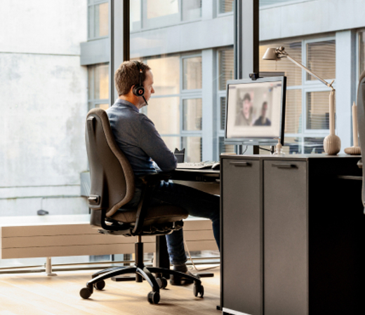 A 7N male staff member on a Zoom call at his computer